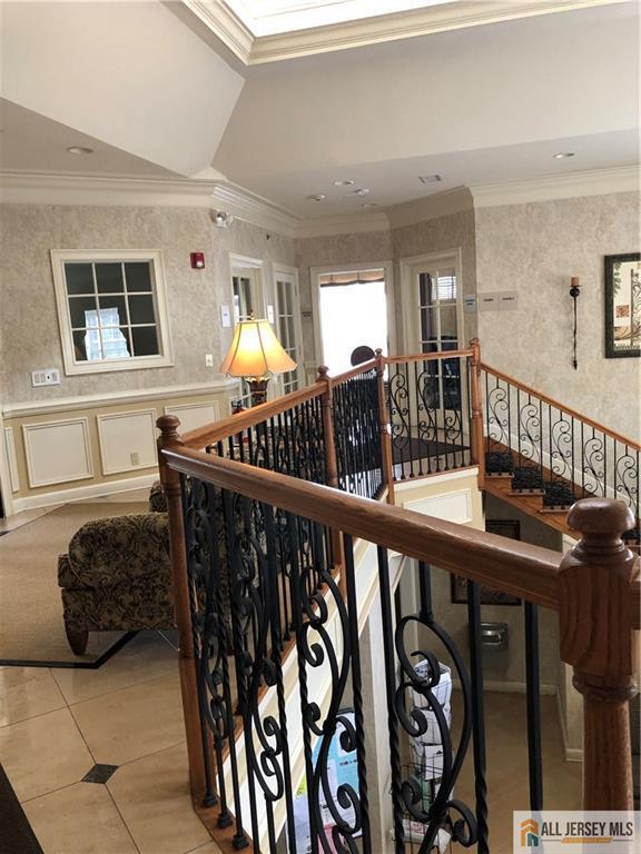 stairs with crown molding and tile patterned floors