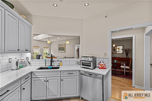 kitchen with stainless steel dishwasher, a sink, backsplash, light wood-style flooring, and recessed lighting