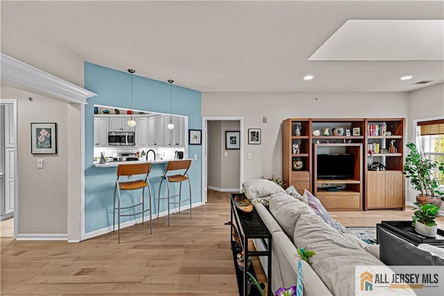 living room featuring light wood-style flooring, recessed lighting, and baseboards