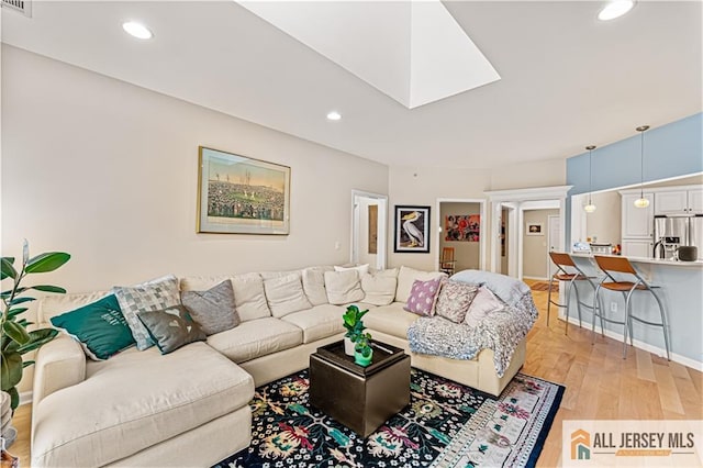 living area featuring light wood finished floors, recessed lighting, and a skylight