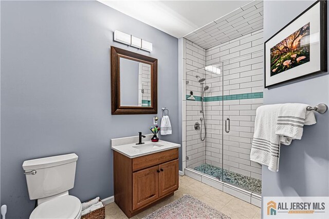 full bathroom with a stall shower, toilet, vanity, and baseboards