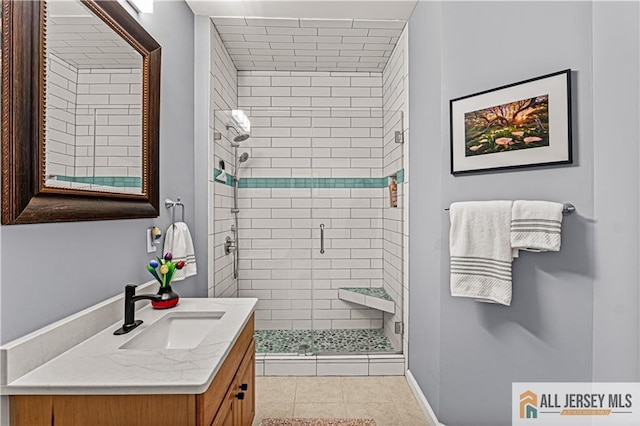 bathroom with a shower stall, vanity, tile patterned flooring, and baseboards