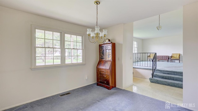 spare room with a chandelier, carpet flooring, and baseboards