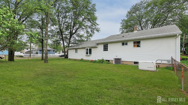 rear view of property with central AC unit, roof with shingles, and a chimney