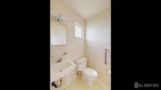 bathroom with toilet, baseboards, and a sink