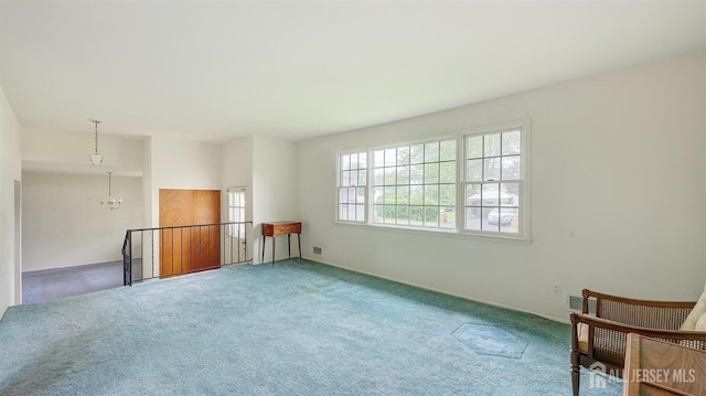 spare room featuring a chandelier, carpet floors, and baseboards