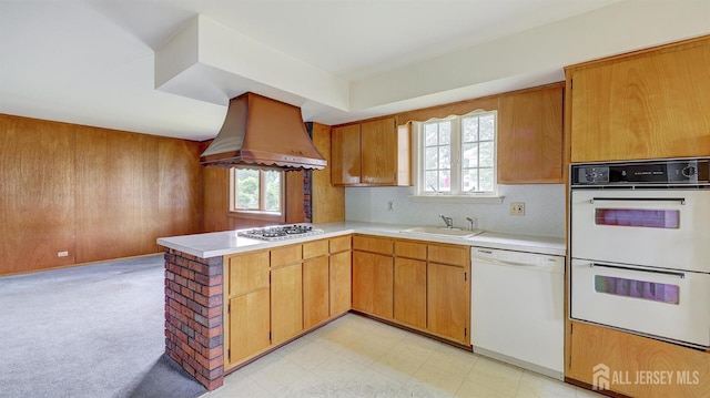 kitchen featuring white appliances, island range hood, a sink, a peninsula, and light countertops