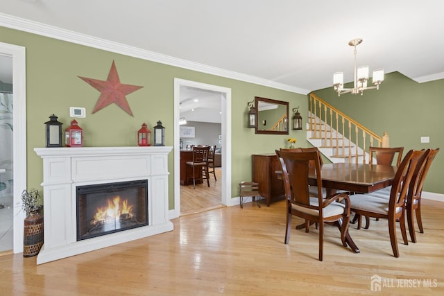 3223 Banta Rd, South Plainfield, NJ 07080 - dining space with light wood-style floors, ornamental molding, a chandelier, baseboards, and a glass covered fireplace