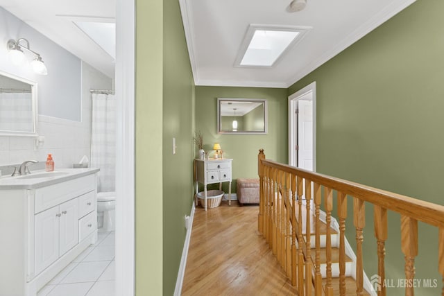 3223 Banta Rd, South Plainfield, NJ 07080 - hall featuring a sink, ornamental molding, a skylight, light tile patterned floors, and tile walls