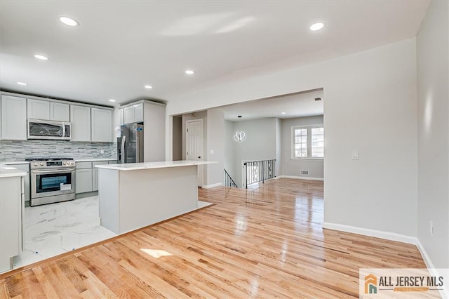 40 Brown Ave, Iselin, NJ 08830 - kitchen featuring appliances with stainless steel finishes, light countertops, recessed lighting, a center island, and decorative backsplash