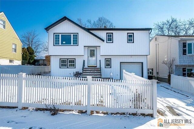 raised ranch with a fenced front yard and a garage