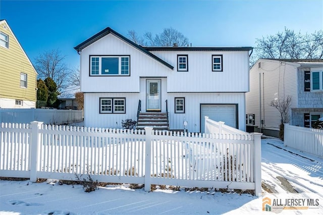 bi-level home featuring a garage and a fenced front yard