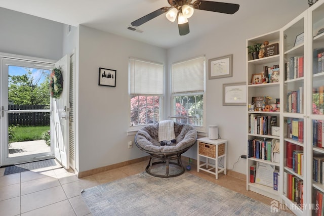 living area with tile patterned flooring, a ceiling fan, and baseboards