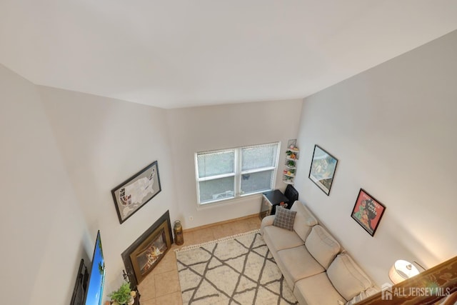 living room with light tile patterned flooring, a glass covered fireplace, and baseboards