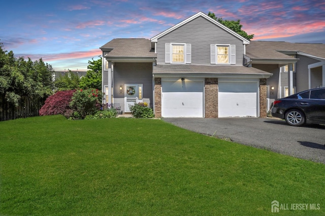 view of front of home featuring asphalt driveway, an attached garage, a lawn, and brick siding