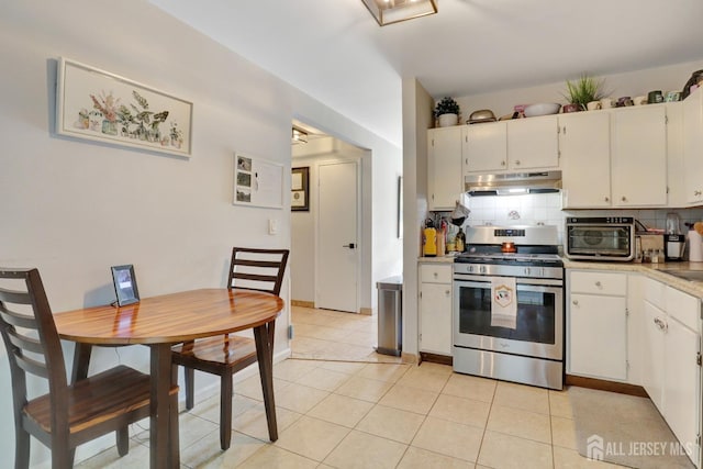 kitchen with gas stove, under cabinet range hood, light countertops, and decorative backsplash
