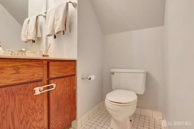 bathroom with vaulted ceiling, toilet, tile patterned floors, baseboards, and vanity