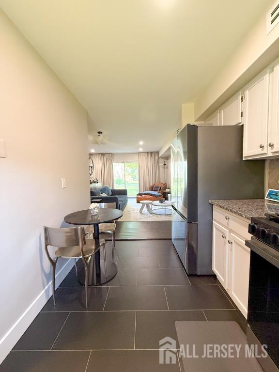 813 Darlington Dr, Old Bridge, NJ 08857 - kitchen featuring appliances with stainless steel finishes, white cabinets, open floor plan, dark tile patterned flooring, and light stone countertops
