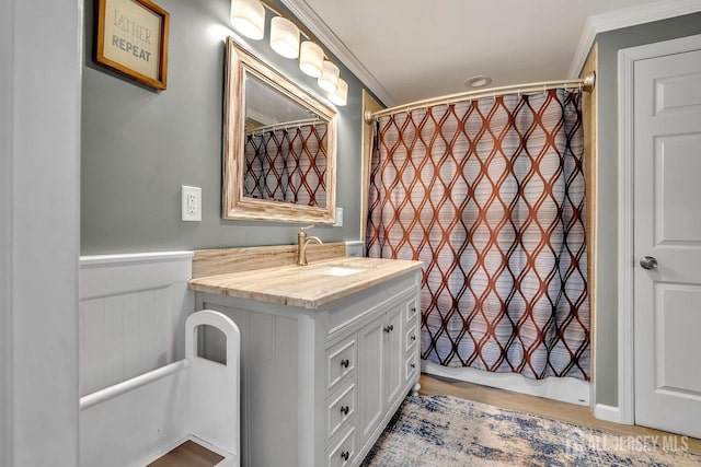 full bathroom featuring vanity, crown molding, and wainscoting