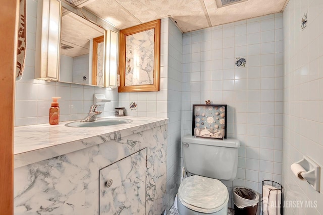 bathroom with tile walls, toilet, vanity, and backsplash