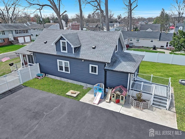 back of house with roof with shingles, a patio, a residential view, and a deck