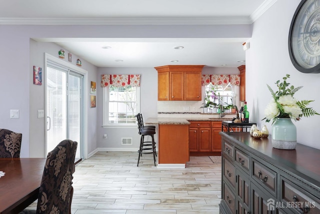 kitchen with a kitchen breakfast bar, brown cabinetry, plenty of natural light, and wood tiled floor