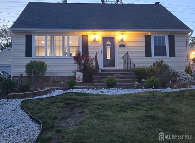 view of front of property with a shingled roof and a front lawn