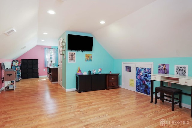interior space featuring light wood-type flooring, baseboards, vaulted ceiling, and visible vents