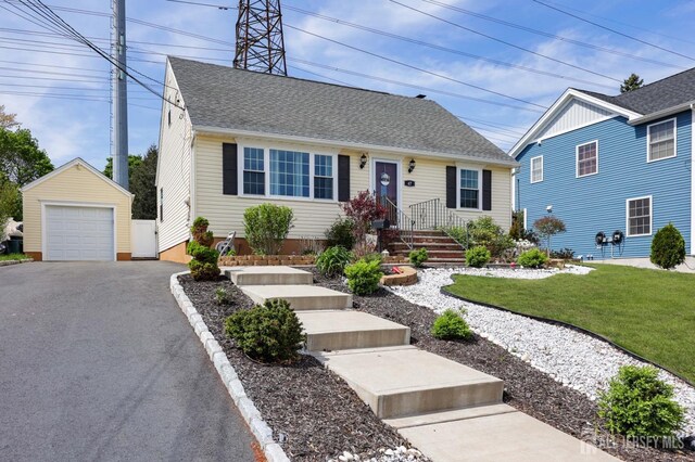view of front facade featuring an outdoor structure, a front lawn, aphalt driveway, roof with shingles, and a detached garage