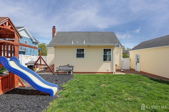 back of property featuring a playground, a chimney, a yard, and a fenced backyard