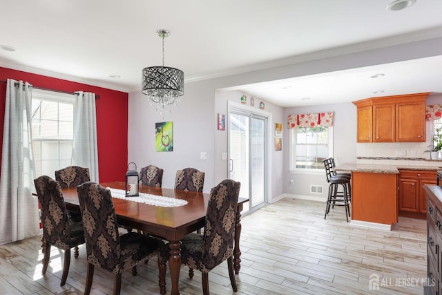 dining room featuring visible vents, ornamental molding, baseboards, light wood finished floors, and a notable chandelier