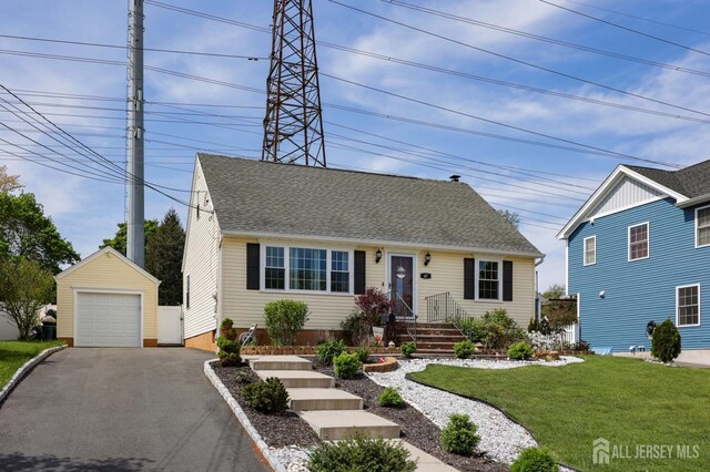 new england style home featuring an outdoor structure, a front lawn, roof with shingles, driveway, and a detached garage