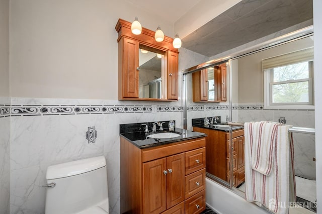 bathroom featuring tile walls, toilet, an enclosed shower, vanity, and wainscoting