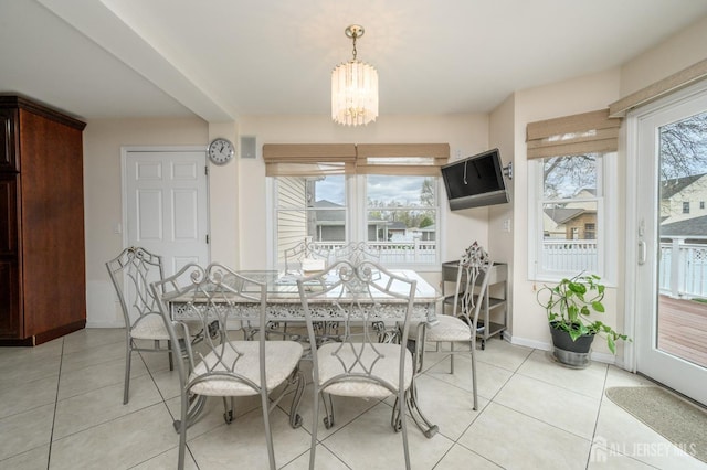 dining room with a chandelier, light tile patterned floors, and baseboards