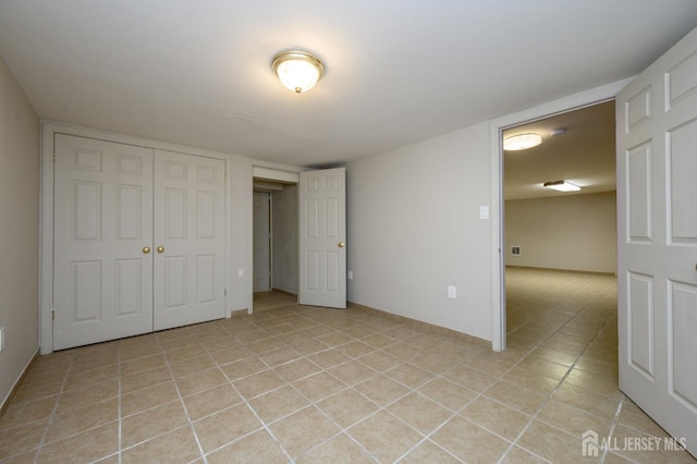 unfurnished bedroom featuring light tile patterned floors and a closet