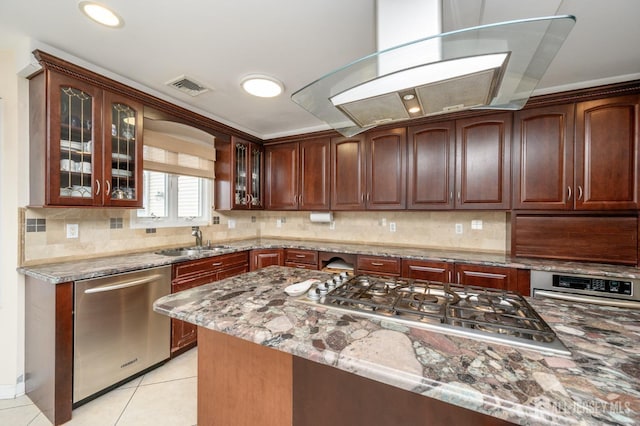 kitchen featuring appliances with stainless steel finishes, a sink, light stone counters, and glass insert cabinets