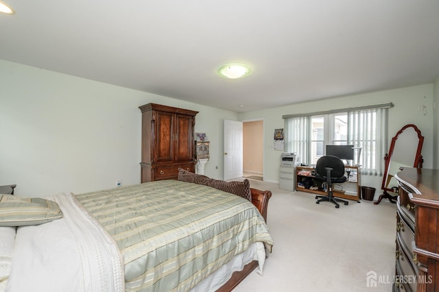 bedroom featuring an office area and light colored carpet