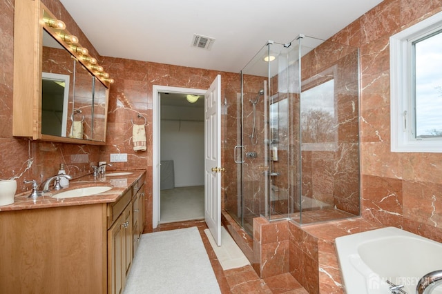 bathroom featuring tile walls, a shower stall, a garden tub, and double vanity