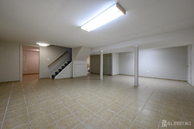 finished below grade area with stairs, light tile patterned floors, and baseboards