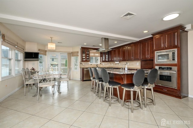 kitchen with stainless steel appliances, baseboards, decorative backsplash, a kitchen bar, and island range hood