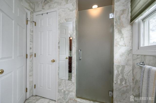 bathroom featuring marble finish flooring and a stall shower