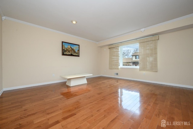 spare room featuring ornamental molding, light wood-style flooring, and baseboards