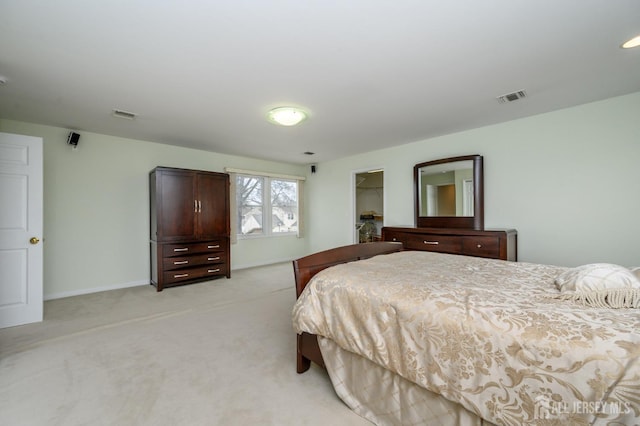 bedroom featuring light colored carpet, baseboards, and a walk in closet