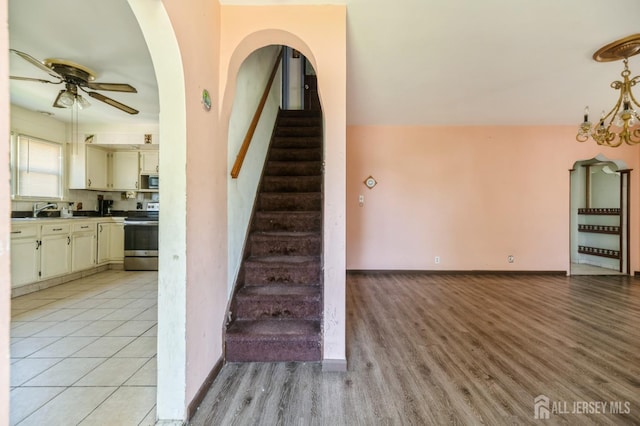 17 New Brunswick Ave, Matawan, NJ 07747 - stairway with a ceiling fan, wood finished floors, arched walkways, and a chandelier
