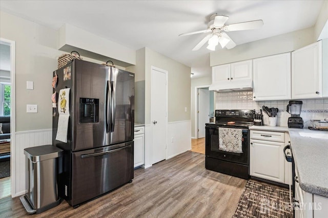 383 S Stump Tavern Rd S, Jackson, NJ 08527 - kitchen featuring stainless steel fridge, black range with electric cooktop, under cabinet range hood, white cabinets, and a wainscoted wall