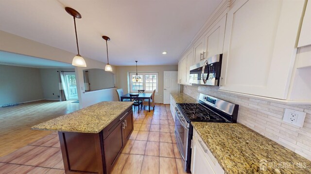 kitchen with stainless steel appliances, hanging light fixtures, light stone counters, white cabinetry, and backsplash