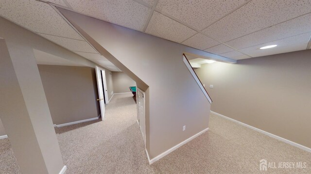 basement with light colored carpet and a paneled ceiling