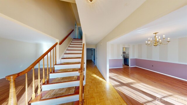 stairway with an inviting chandelier and parquet flooring