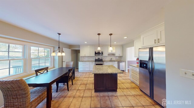 kitchen with stainless steel appliances, decorative light fixtures, a center island, and white cabinets