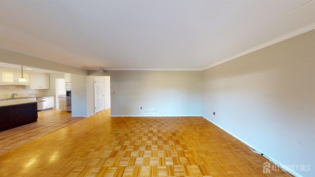 unfurnished living room with light parquet flooring, ornamental molding, and sink